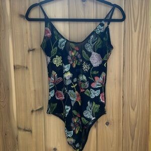 Pretty sheer flower bordered bodysuit With adjustable straps and snap enclosure.